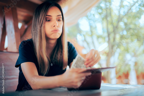 Worried Woman Paying an Expensive Price at the Restaurant. Unhappy customer having to pay more for food in a diner 
 photo