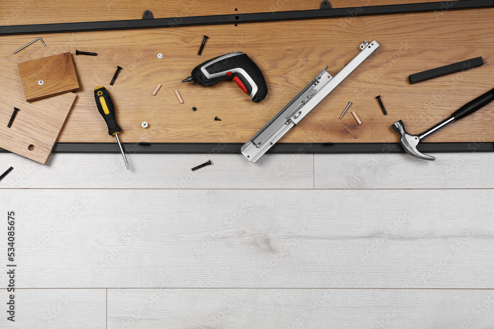 Flat lay composition with furniture assembly parts and tools on white wooden floor. Space for text Flat lay composition with furniture assembly parts and tools on white wooden floor. Space for text