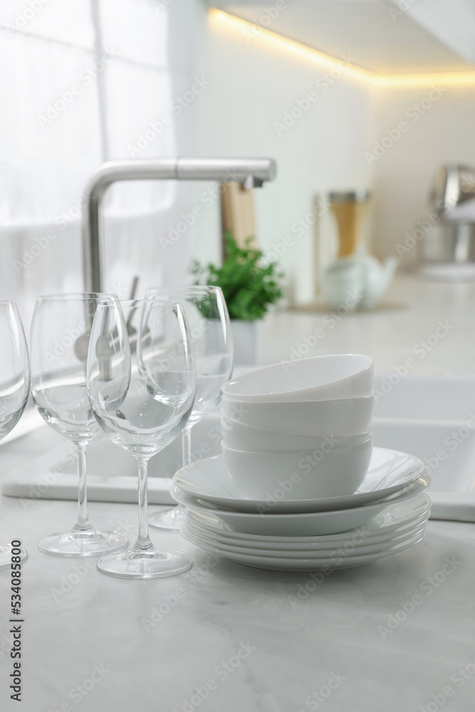 Different clean dishware and glasses on countertop near sink in kitchen