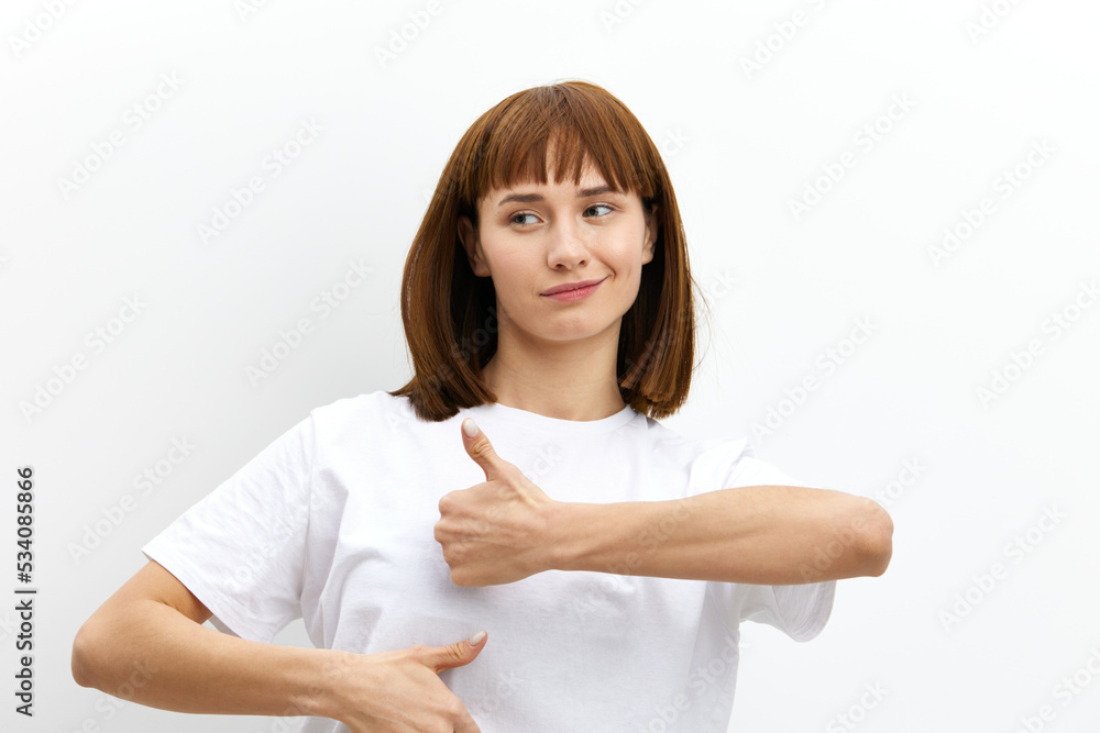 a happy, joyful woman with red hair and a beautiful hairstyle looks at the camera smiling and gives a thumbs-up gesture as a sign of approval a happy, joyful woman with red hair and a beautiful hairstyle looks at the camera smiling and gives a thumbs-up gesture as a sign of approval