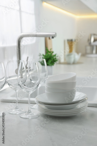 Different clean dishware and glasses on countertop near sink in kitchen