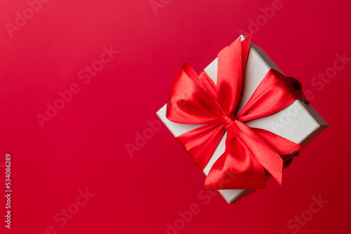 Gorgeous festive Christmas banner or header, holiday present on red background. Christmas floating gift box on red. Holiday season, New Year. Copy space for text.