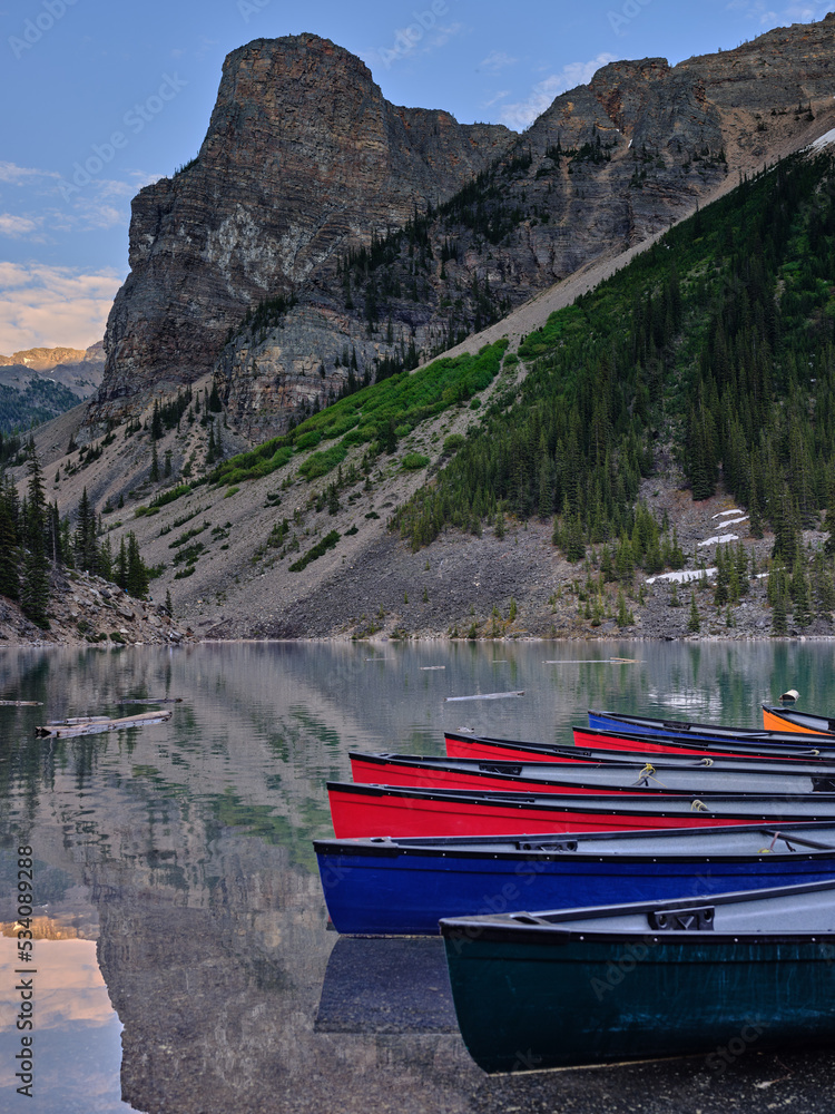 Rental canoes sit idle on Moraine Lake with the rugged mountain peaks in the background