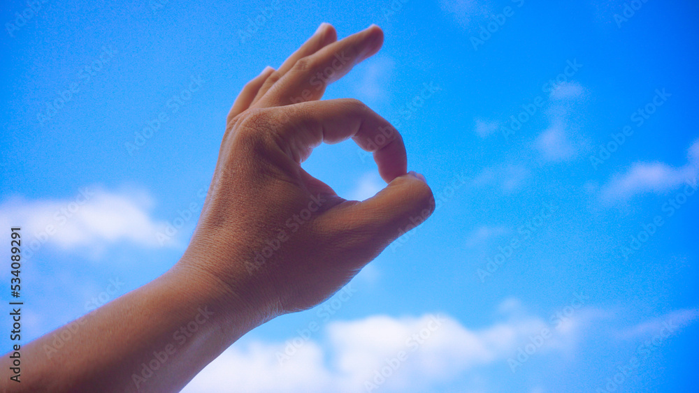Male fist isolated on blue sky background. Asian hand make sign OK. Counting, brave, masculinity concept Male fist isolated on blue sky background. Asian hand make sign OK. Counting, brave, masculinity concept