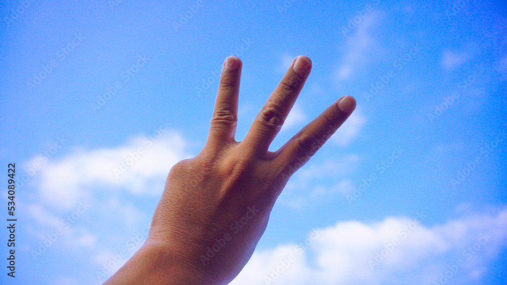 Male fist isolated on blue sky background. Asian hand make sign number 3. Counting, brave, masculinity concept