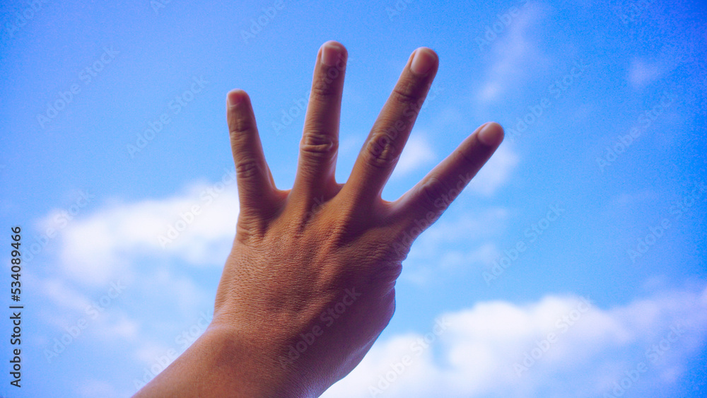 Male fist isolated on blue sky background. Asian hand make sign number 4. Counting, brave, masculinity concept Male fist isolated on blue sky background. Asian hand make sign number 4. Counting, brave, masculinity concept