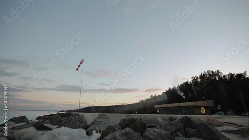shore of a frozen lake with a forest and a house