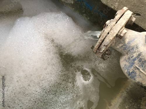 A water flow meter that delivers industrial wastewater to a wastewater treatment plant. Water is yellowish and foamy