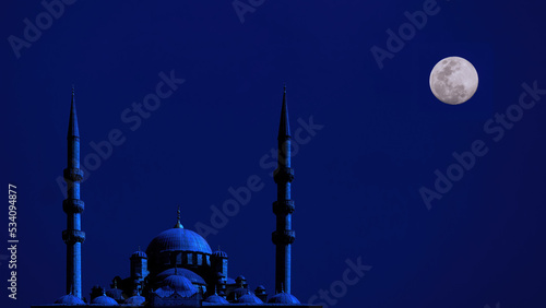 silhouette islamic mosque at night with moon on blue sky photo