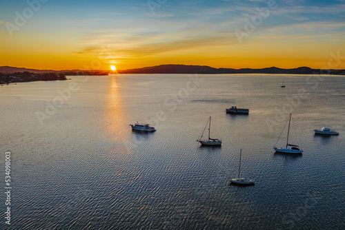 Aerial sunrise waterscape with boats and high cloud photo