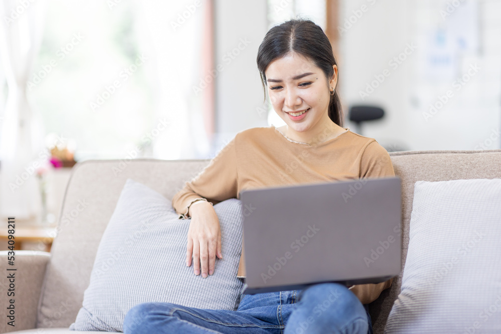 Beautiful Young Asian woman using laptop computer on sofa at home, shopping online with internet in happy mood and Relax part time concept Beautiful Young Asian woman using laptop computer on sofa at home, shopping online with internet in happy mood and Relax part time concept
