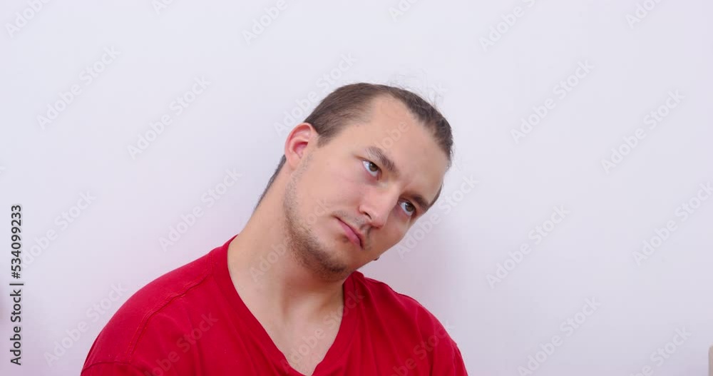 Young guy in a red t-shirt and with a stylish hairstyle does neck exercises, front view. Necessary activity and exercises for joints and muscles with a sedentary lifestyle. Young guy in a red t-shirt and with a stylish hairstyle does neck exercises, front view. Necessary activity and exercises for joints and muscles with a sedentary lifestyle.