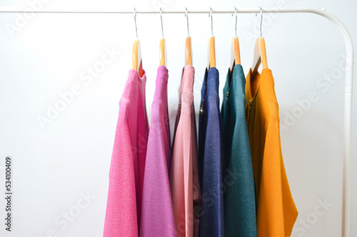 Fashion clothes on clothing rack - bright colorful closet. Summer home wardrobe.