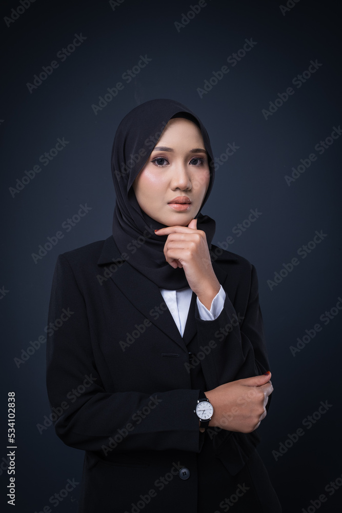 Portrait of an attractive Muslim woman wearing business attire and hijab with a corporate pose isolated on grey background. For image cut-out for technology, business or finance. Portrait of an attractive Muslim woman wearing business attire and hijab with a corporate pose isolated on grey background. For image cut-out for technology, business or finance.