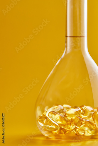 Omega-3 fatty acid capsules on a blue background in a flask. The concept of medicine and healthy living. Vertical photo.