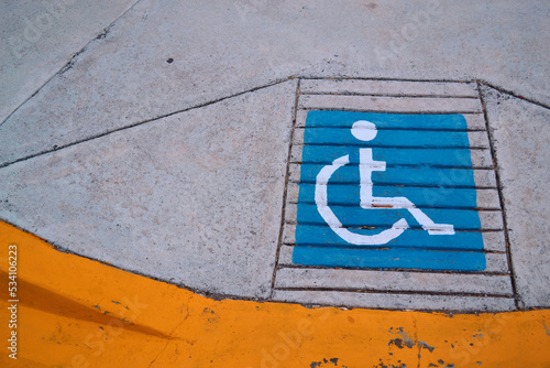 Blue sign of disabled persons, painted in the sidewalk.