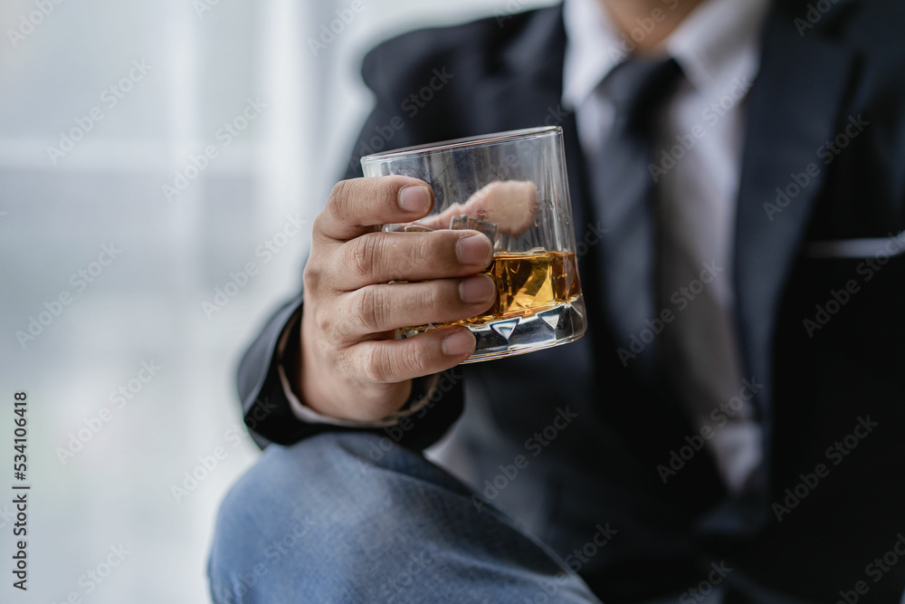 The bartender holds a glass of whiskey and ice to the male guest. The rest of the concept in the bar Close-up of serious businessman holding whiskey showing executive privilege concept. The bartender holds a glass of whiskey and ice to the male guest. The rest of the concept in the bar Close-up of serious businessman holding whiskey showing executive privilege concept.