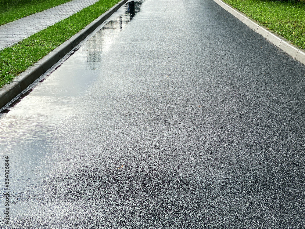 Obraz premium empty new asphalt road on a rainy day. wet road surface with water puddles after rain.