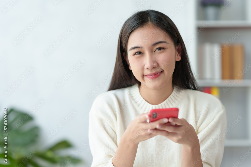 Beautiful young Asian woman smiling enjoying social media on mobile phone. Beautiful young Asian woman smiling enjoying social media on mobile phone.