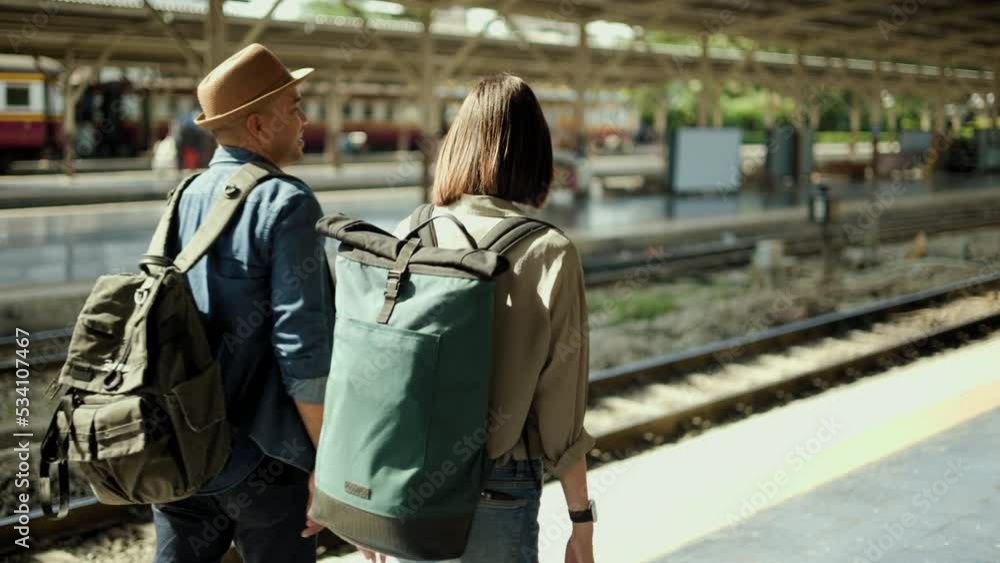 Couple asian traveller with bag on honeymoon travel by train. Happy Backpacker Man and woman near platform train station. Planning tourist on vacation time holiday weekend. Go Everywhere concept. Couple asian traveller with bag on honeymoon travel by train. Happy Backpacker Man and woman near platform train station. Planning tourist on vacation time holiday weekend. Go Everywhere concept.
