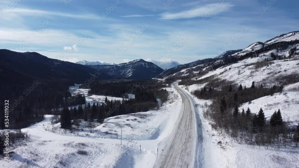 Revealing shot of the empty highway with mountains on background with a lot of snow Revealing shot of the empty highway with mountains on background with a lot of snow