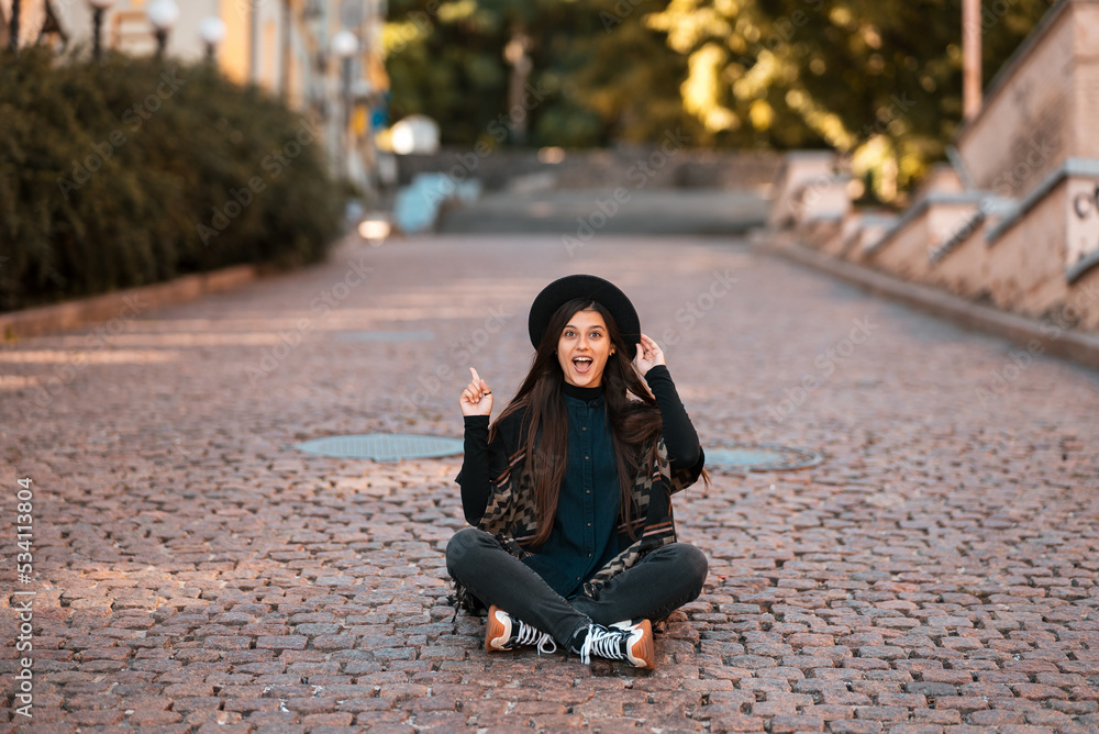Fototapeta premium Young woman sitting at city show finger up, new idea