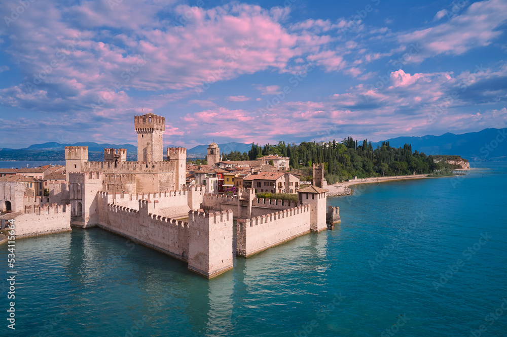 Scaligero Castle at sunrise, Lake Garda, Italy. Scaligero Castle aerial view. Pink clouds over Scaligero Castle aerial view.