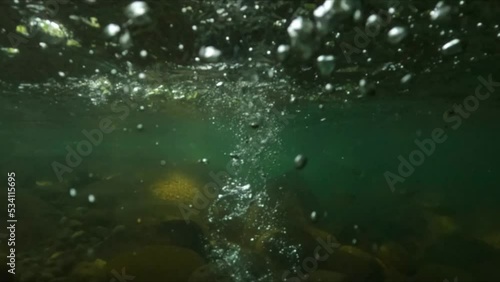 Slow motion underwater shot of a stone falling into a river photo