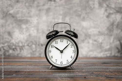 Wallpaper Mural Alarm Clock analog classic vintage retro style black on the wooden table with background bare plaster or loft style. Torontodigital.ca
