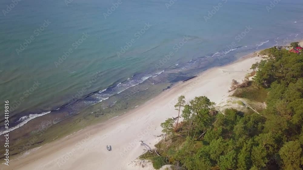 Aerial birdseye view of Baltic sea coast on a sunny day, white sand seashore dunes damaged by waves, pine tree forest, coastal erosion, climate changes, wide angle drone shot moving forward Aerial birdseye view of Baltic sea coast on a sunny day, white sand seashore dunes damaged by waves, pine tree forest, coastal erosion, climate changes, wide angle drone shot moving forward