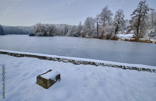 Gros bloc de pierre sur la rive de l'étang dans un paysage enneigé photo