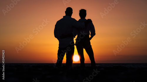 Kobieta i mężczyzna przytuleni na tle zachodzącego słońca