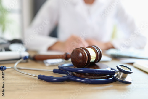 Closeup of judge gavel of stethoscope doctor in background writing notes
