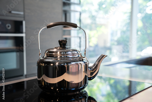 Stainless Water Crow or Vintage Kettle tea pot on electronic stove in modern Kitchen room. photo