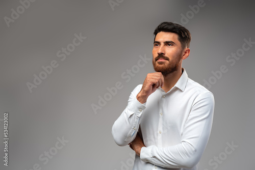 Studuo shot of thinking businessman standing over gray background photo