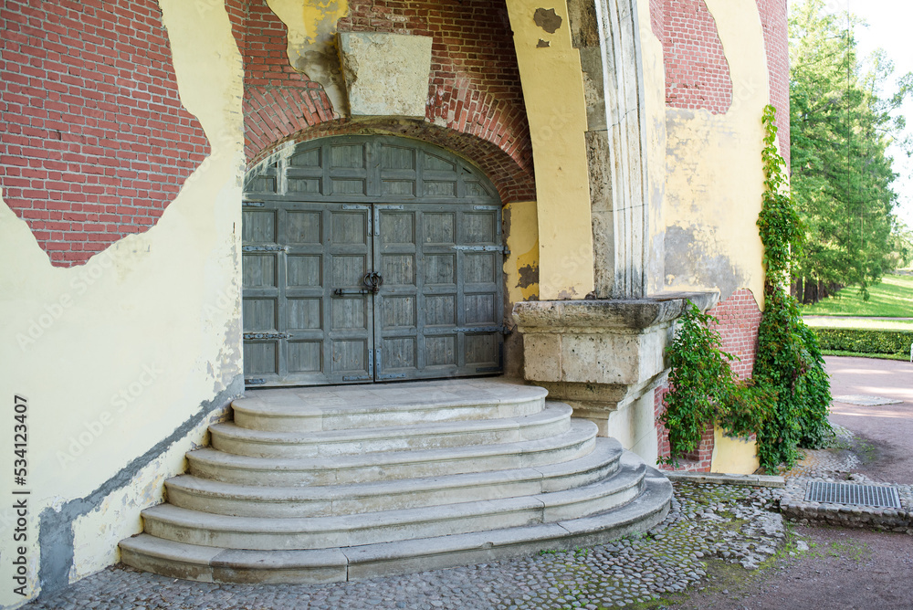 An ancient wooden door with steps with ivy of an abandoned tower or house. An ancient wooden door with steps with ivy of an abandoned tower or house.