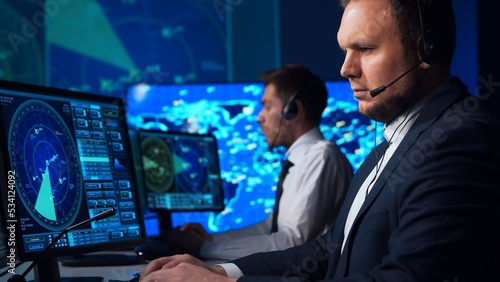 Workplace of the air traffic controllers in the control tower. Team of professional aircraft control officers works using radar, computer navigation and digital maps. Aviation concept.