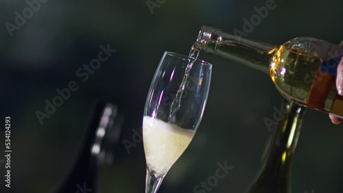Tilted clip pouring chilled champagne from a bottle into a clear glass flute
