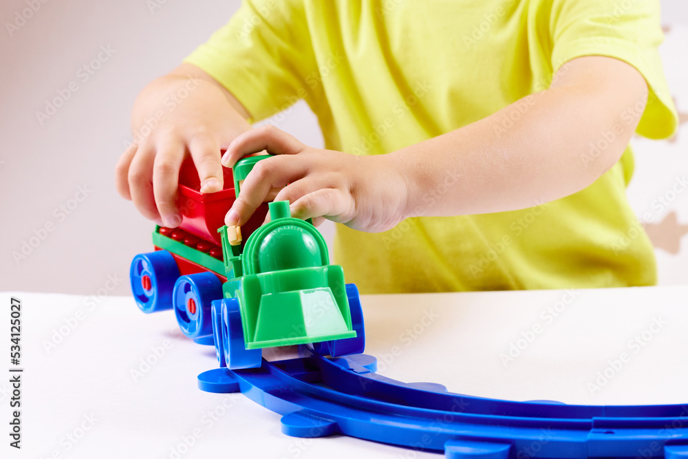 A small child plays with a train and a railroad. Games at home or in kindergarten. selective focus
