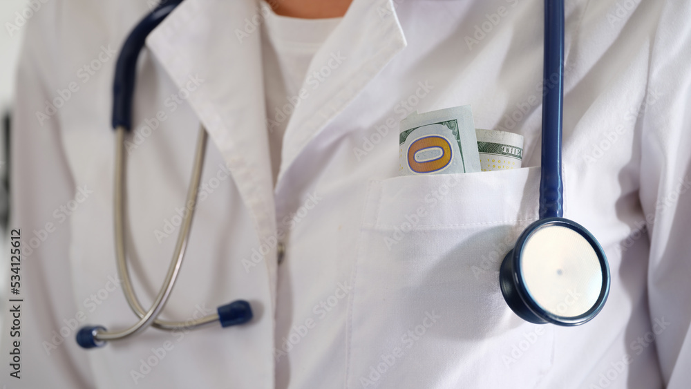 Medical doctor woman with hundred dollar bills in pocket closeup Medical doctor woman with hundred dollar bills in pocket closeup