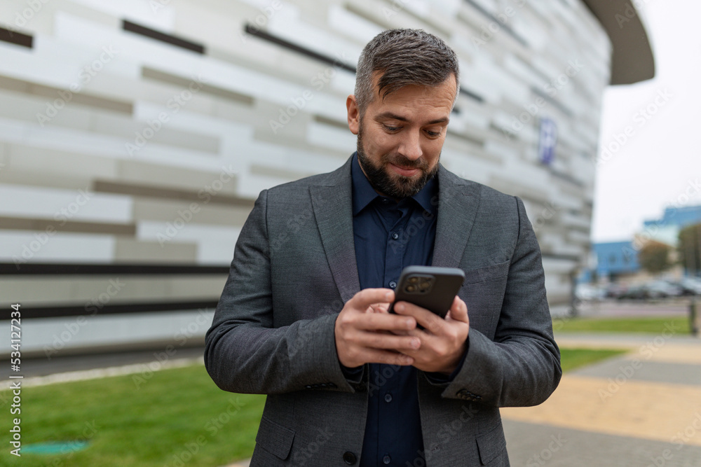 an adult business man in a classic suit looks at the phone screen with surprise an adult business man in a classic suit looks at the phone screen with surprise