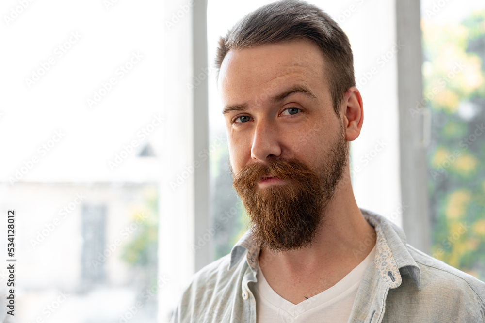 Bearded smiling handsome young man standing alone at home Bearded smiling handsome young man standing alone at home