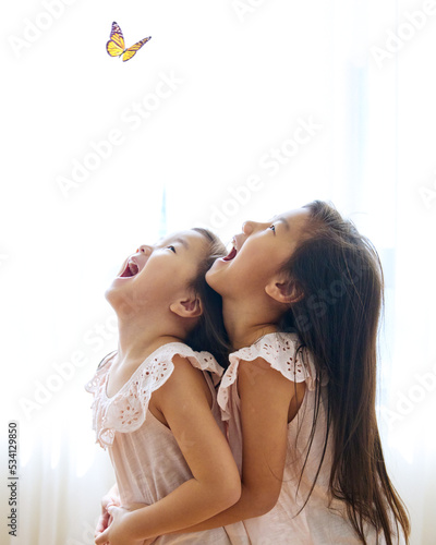2 cute little lovely asian sisters laugh happily while looking to butterfly