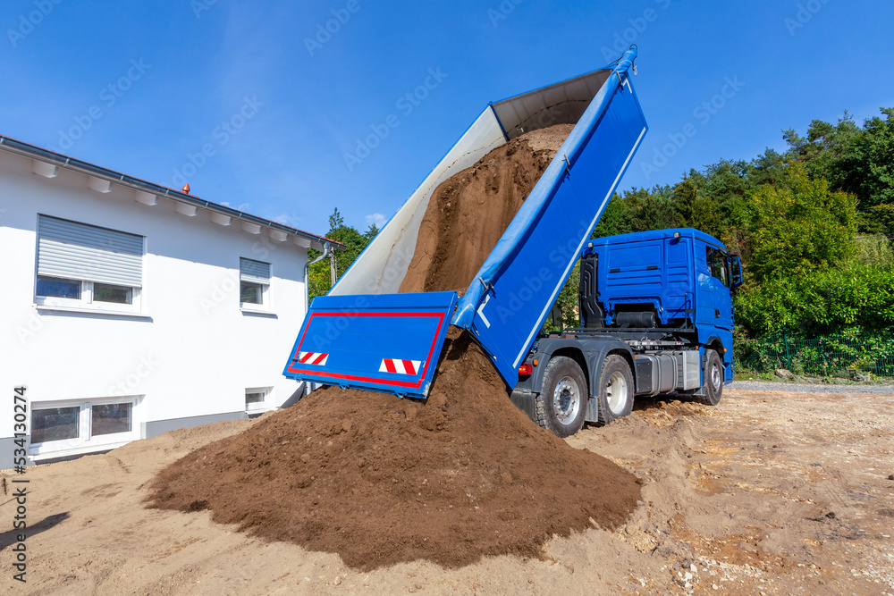 unloading the truck with potting soil from the truck bed at the construction site