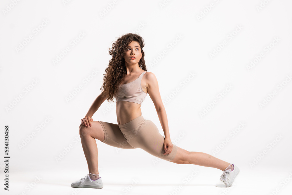 Portrait of sporty fit beautiful young brunette woman in sportswear bra and black pants working out, doing Utthita Trikonasana, Extended Triangle pose, studio full length, isolated, white background Portrait of sporty fit beautiful young brunette woman in sportswear bra and black pants working out, doing Utthita Trikonasana, Extended Triangle pose, studio full length, isolated, white background