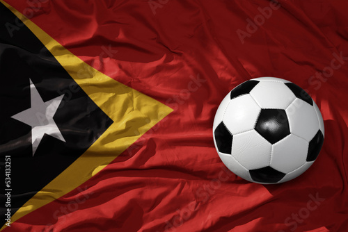 vintage football ball on the waveing national flag of east timor background. 3D illustration