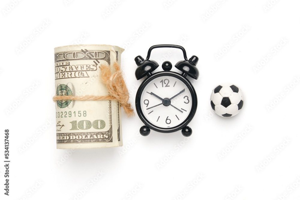 Flatlay picture of alarm clock with miniature ball and fake money. Football business concept. Flatlay picture of alarm clock with miniature ball and fake money. Football business concept.