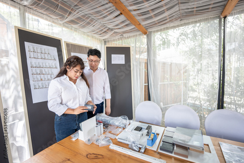 Asian Man and woman are choosing materials for interior decorations placed on a brown wooden table. photo