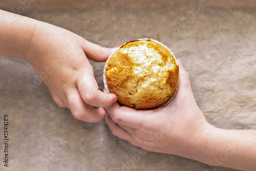 Children's hands reach for a freshly baked vanilla cupcake