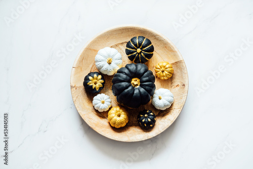 Black Gold White Pumpkin For Halloween and Thanksgiving. Minimal Top view flat lay autumn composition with painting black golden trendy pumpkins in round plate